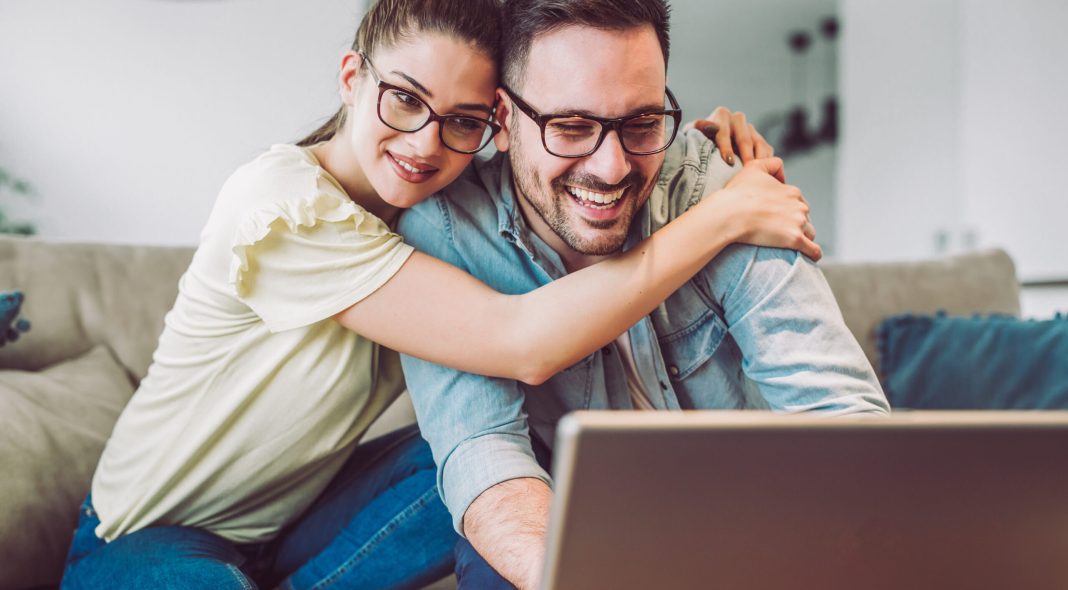 Happy couple with laptop spending time together at home